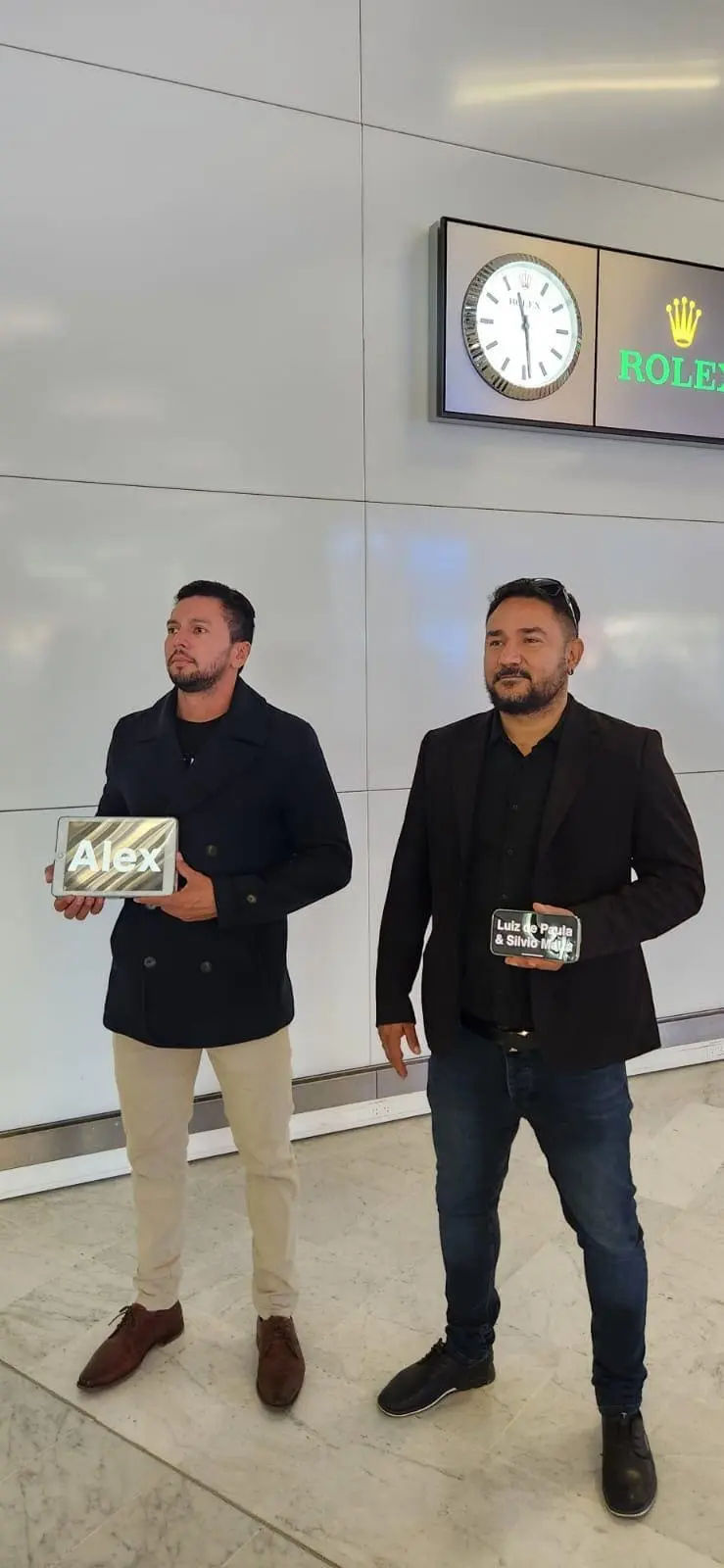 Motorista esperando no aeroporto com um cartaz com o nome do cliente.